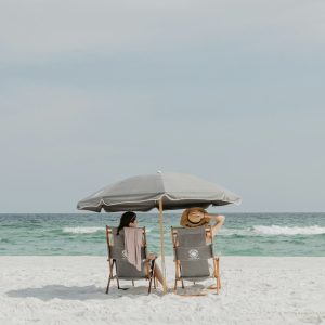 Photo by Briana Tozour two people under beach umbrella near shoreline